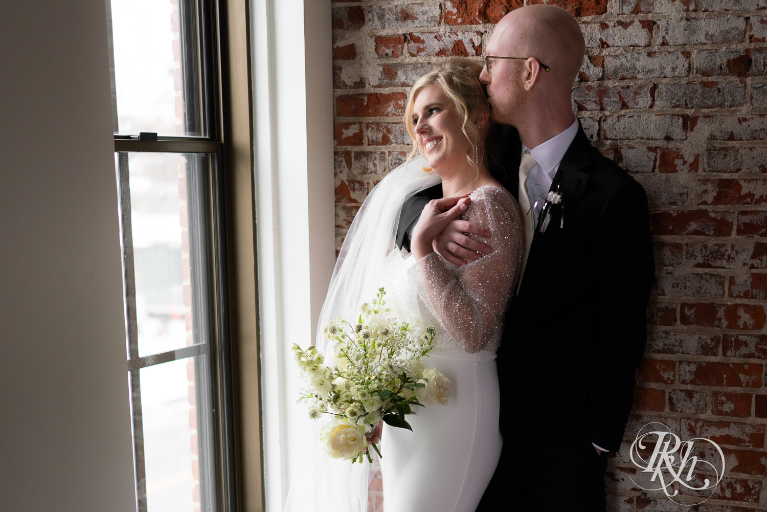 Bride and groom kiss by a window at Gatherings at Station 10 in Saint Paul, Minnesota.