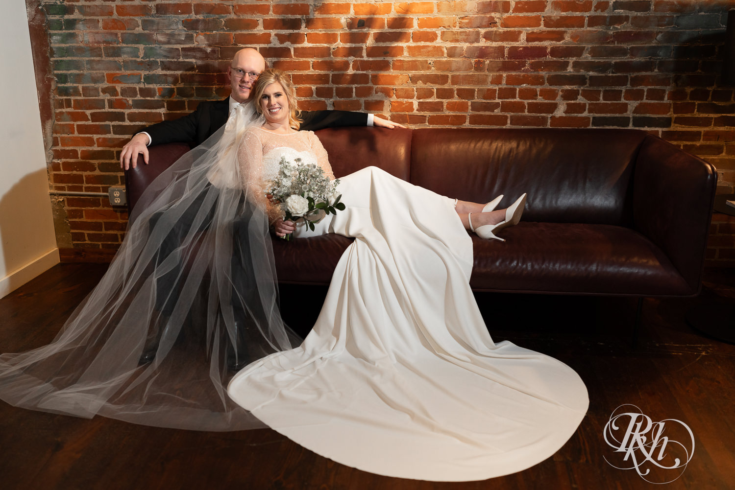 Bride and groom smile on a couch at Gatherings at Station 10 in Saint Paul, Minnesota.