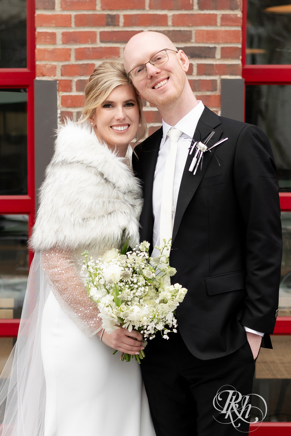 Bride and groom smile outside Gatherings at Station 10 in Saint Paul, Minnesota on winter wedding day.