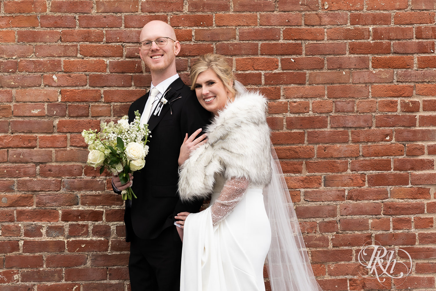 Bride and groom smile outside Gatherings at Station 10 in Saint Paul, Minnesota on winter wedding day.