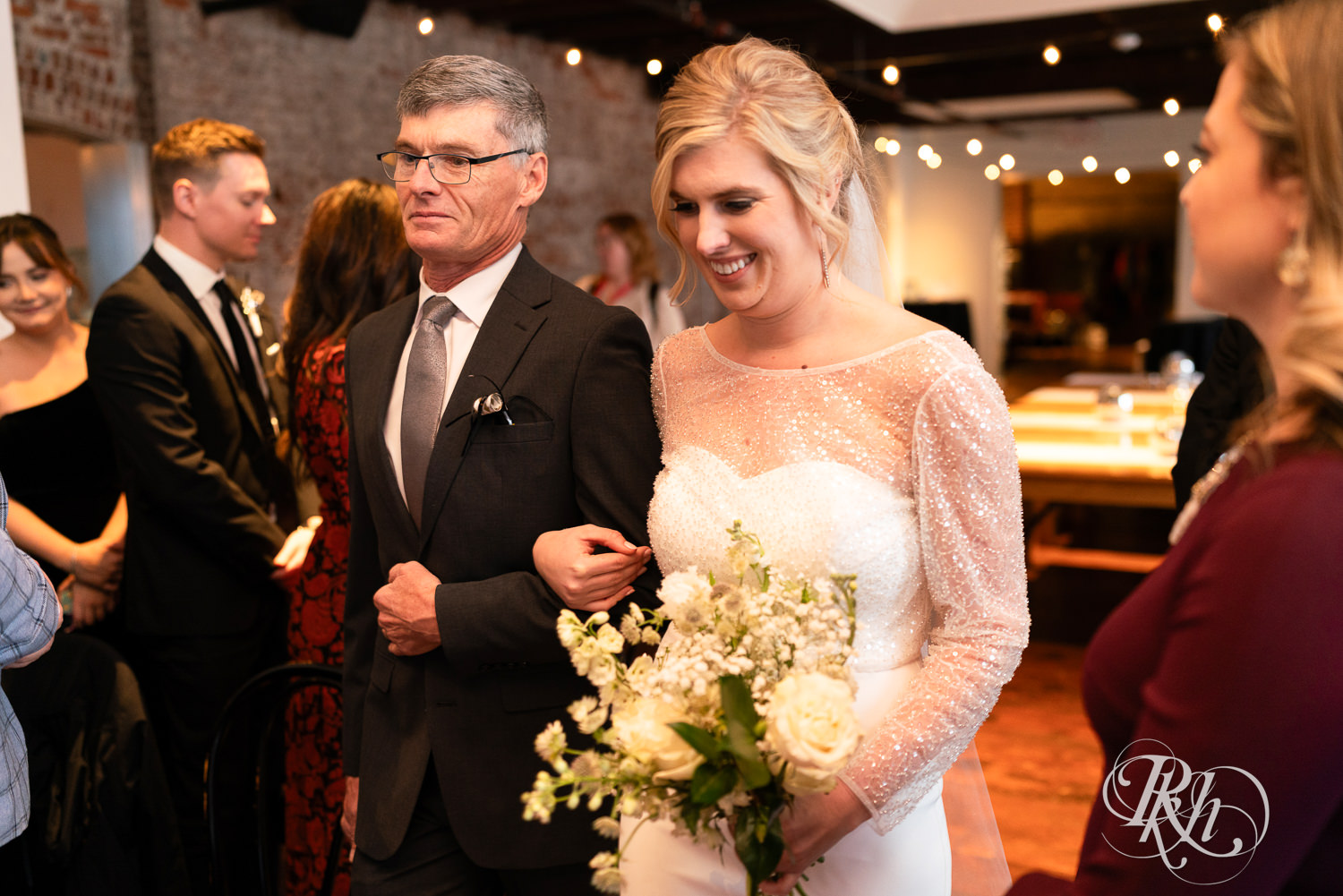 Bride walks down the aisle with dad during indoor wedding ceremony at Gatherings at Station 10 in Saint Paul, Minnesota.
