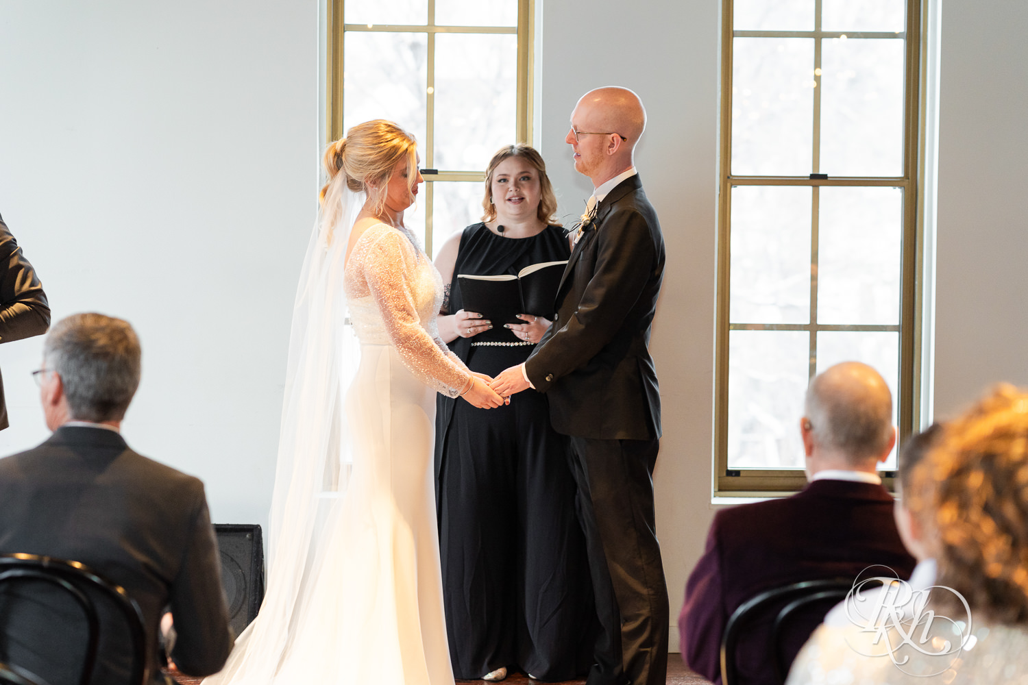 Bride and groom smile during indoor wedding ceremony at Gatherings at Station 10 in Saint Paul, Minnesota.