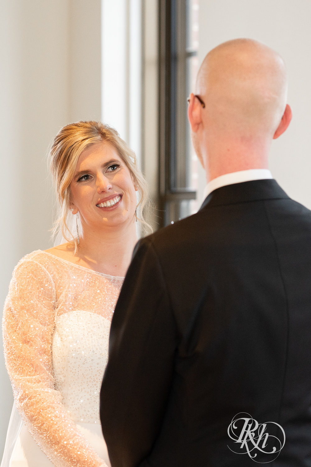 Bride and groom smile during indoor wedding ceremony at Gatherings at Station 10 in Saint Paul, Minnesota.