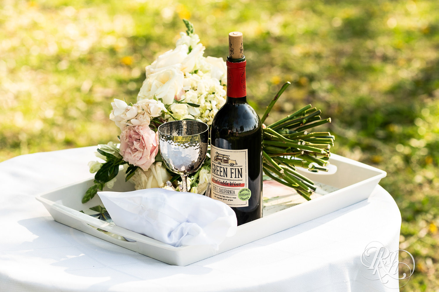 Flowers, a chalice and a bottle of wine on a small table. 