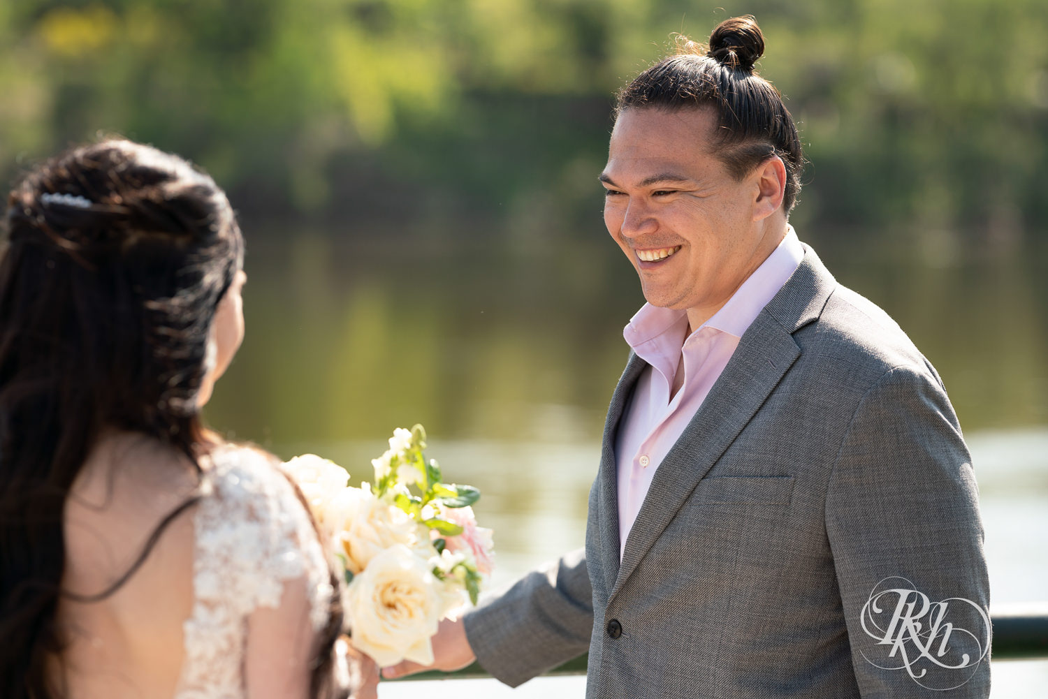 Groom smiles at bride during first look at Boom Island Park in Minneapolis, Minnesota.