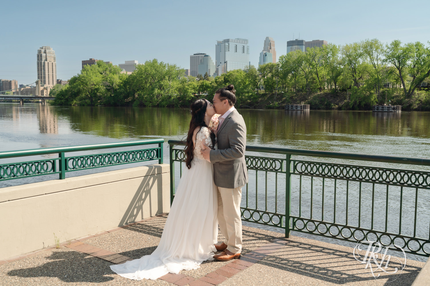 Bride and groom kiss on wedding day in Boom Island Park in Minneapolis, Minnesota.