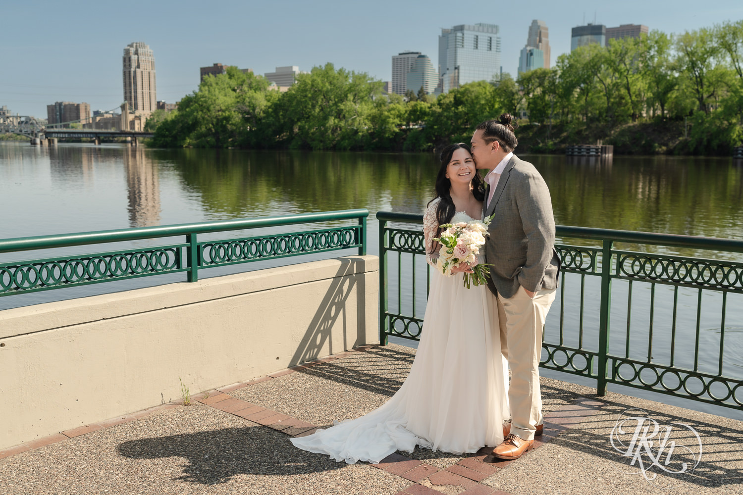 Bride and groom smile on wedding day in Boom Island Park in Minneapolis, Minnesota.