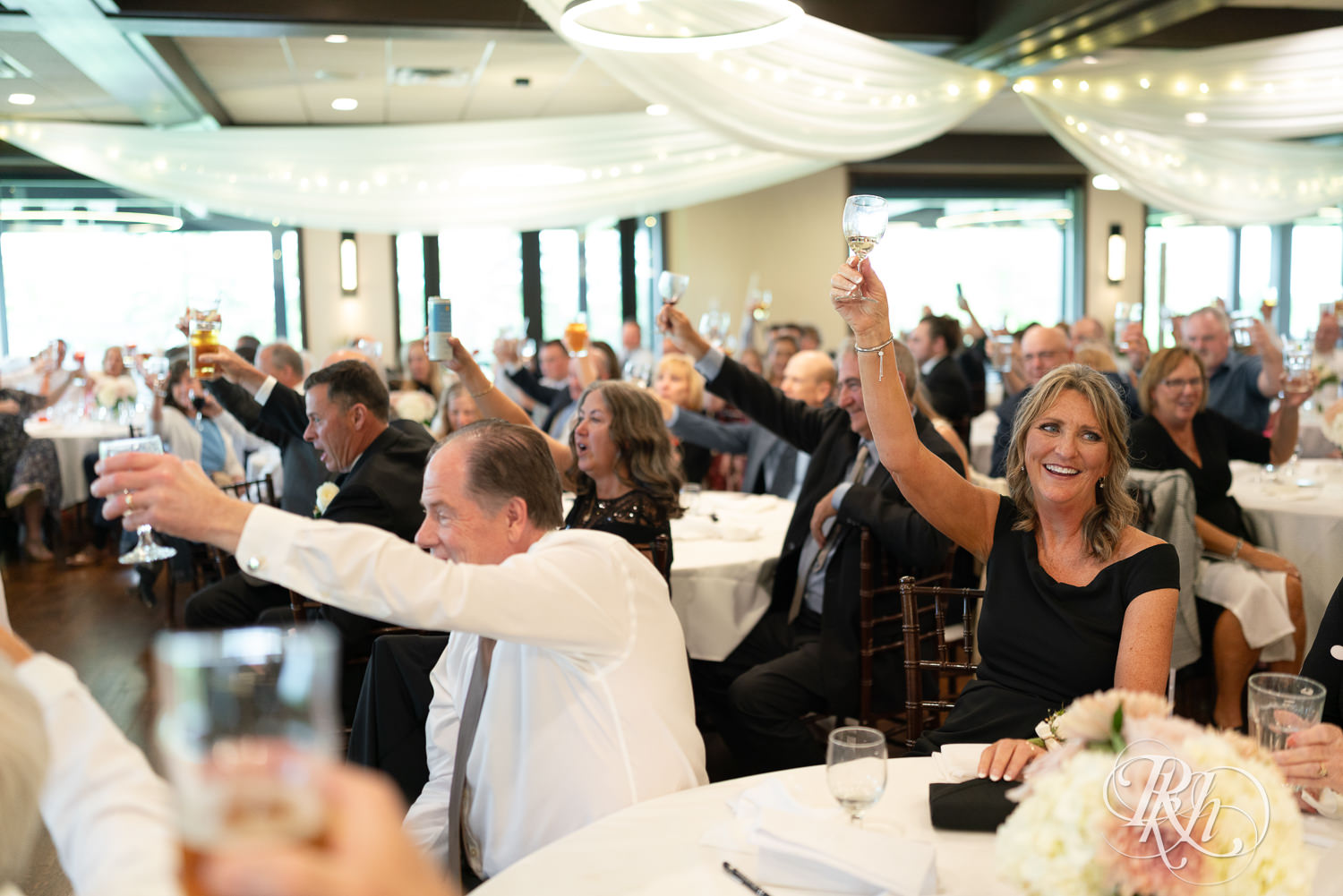 Wedding party and guests laugh during wedding reception at Olympic Hills Golf Club in Eden Prairie, Minnesota.