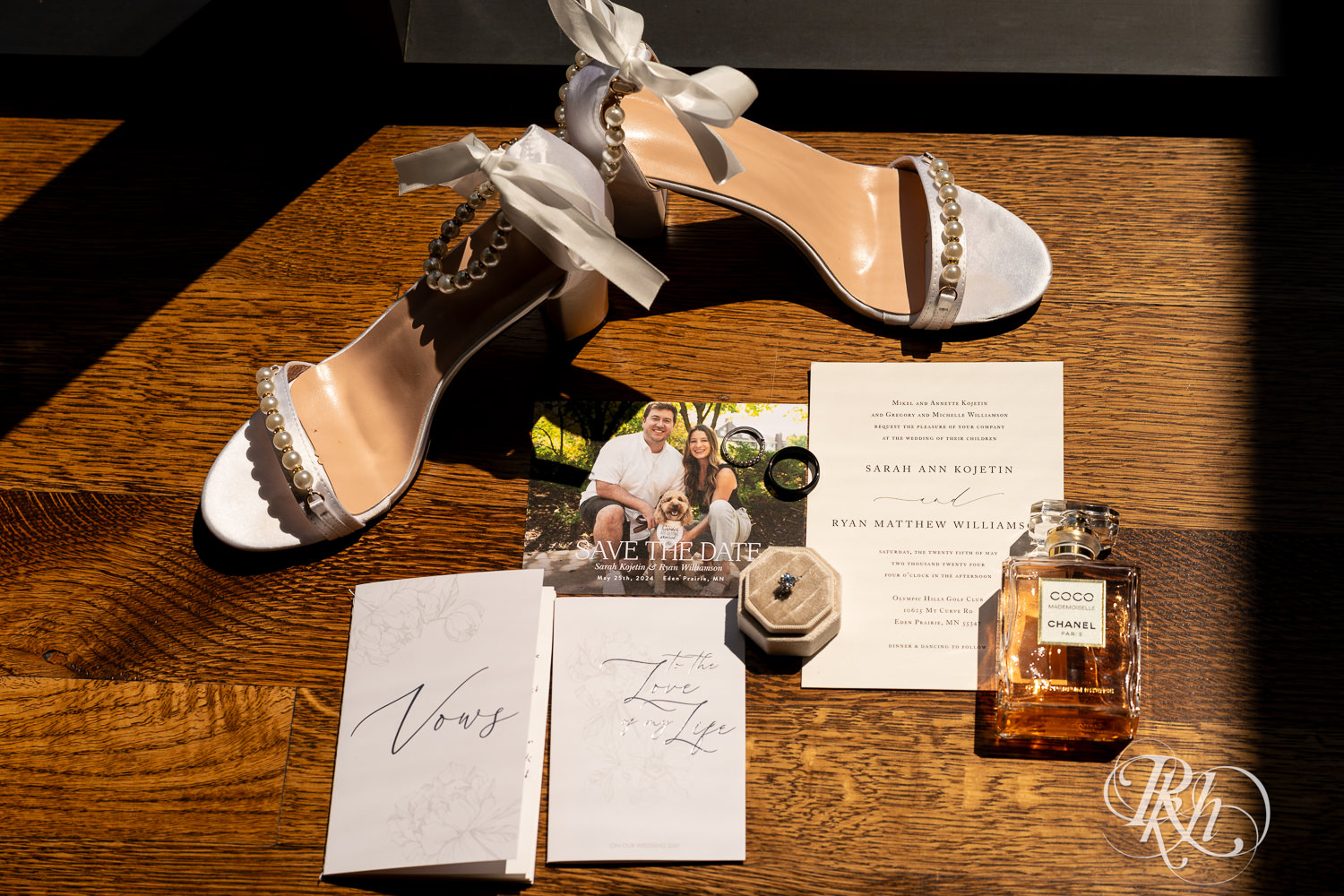 Wedding details in including invitation, shoes, perfume, and rings at Olympic Hills Golf Club in Eden Prairie, Minnesota.