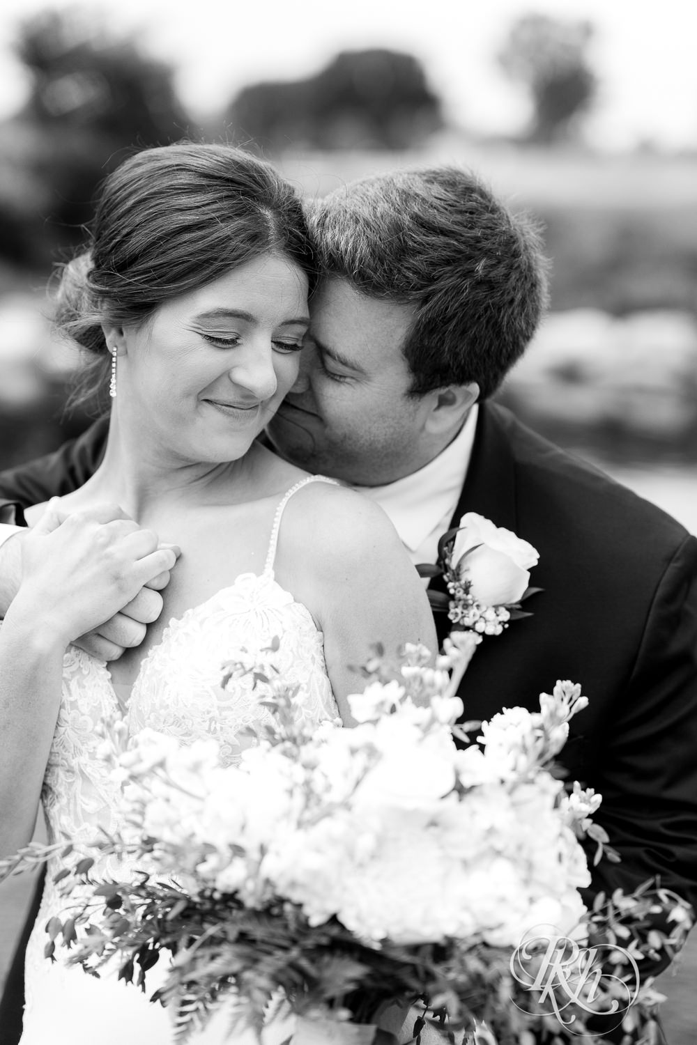 Bride and groom kiss in front of water on wedding day at Olympic Hills Golf Club in Eden Prairie, Minnesota.