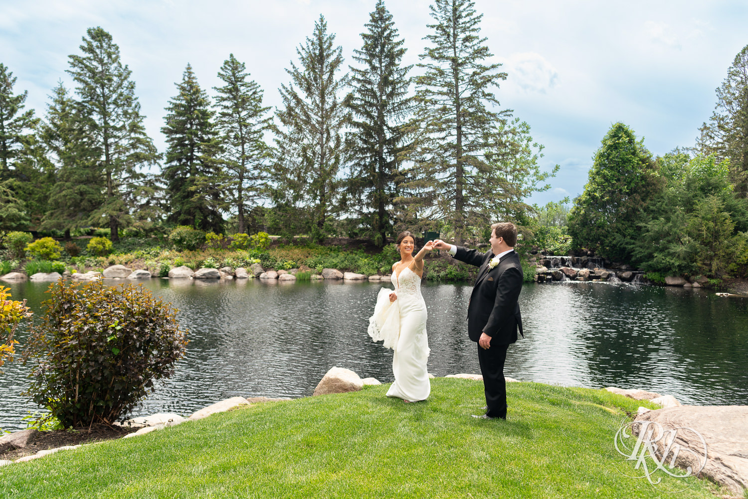 Bride and groom dance in front of water on wedding day at Olympic Hills Golf Club in Eden Prairie, Minnesota.