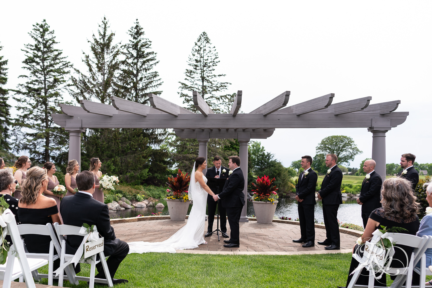 Bride and groom smile during wedding ceremony at Olympic Hills Golf Club in Eden Prairie, Minnesota.