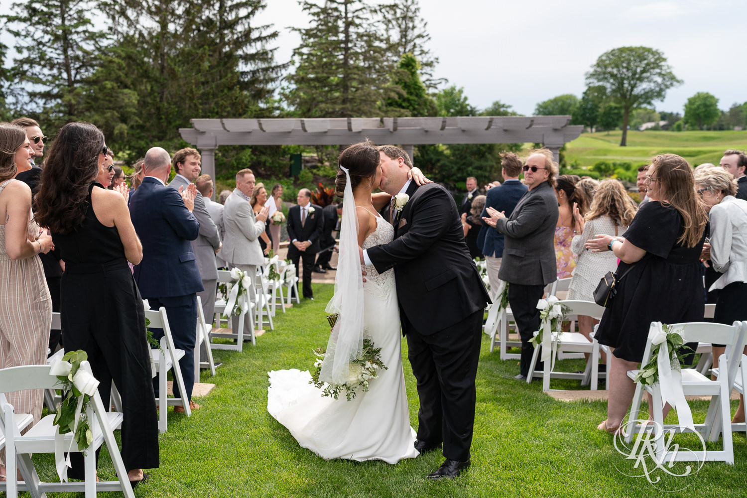 Bride and groom kiss after wedding ceremony at Olympic Hills Golf Club in Eden Prairie, Minnesota.