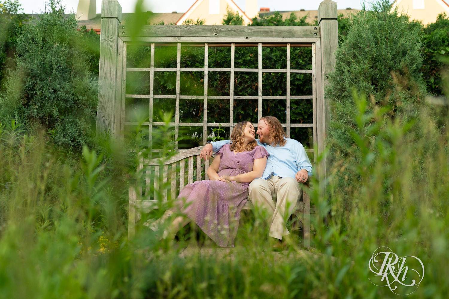 Man in blue shirt and woman in purple dress smile on a bench in a garden at Centennial Lakes Park in Edina, Minnesota.