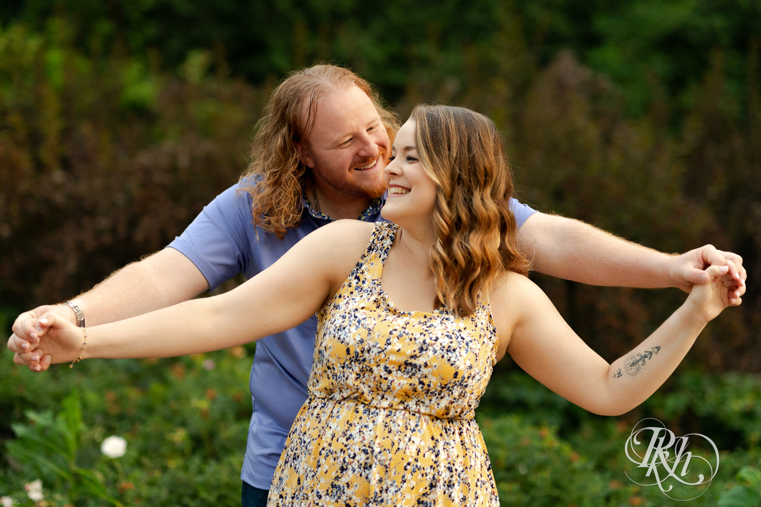 Man in blue shirt and woman in purple dress smile in a garden at Centennial Lakes Park in Edina, Minnesota.