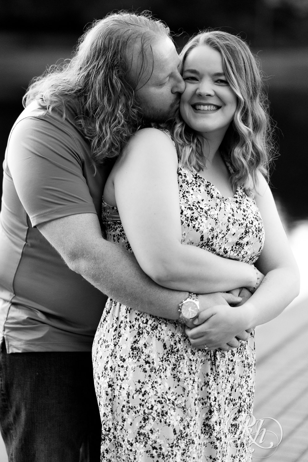 Man in blue shirt and woman in flower dress smile in front of the water at Centennial Lakes Park in Edina, Minnesota.