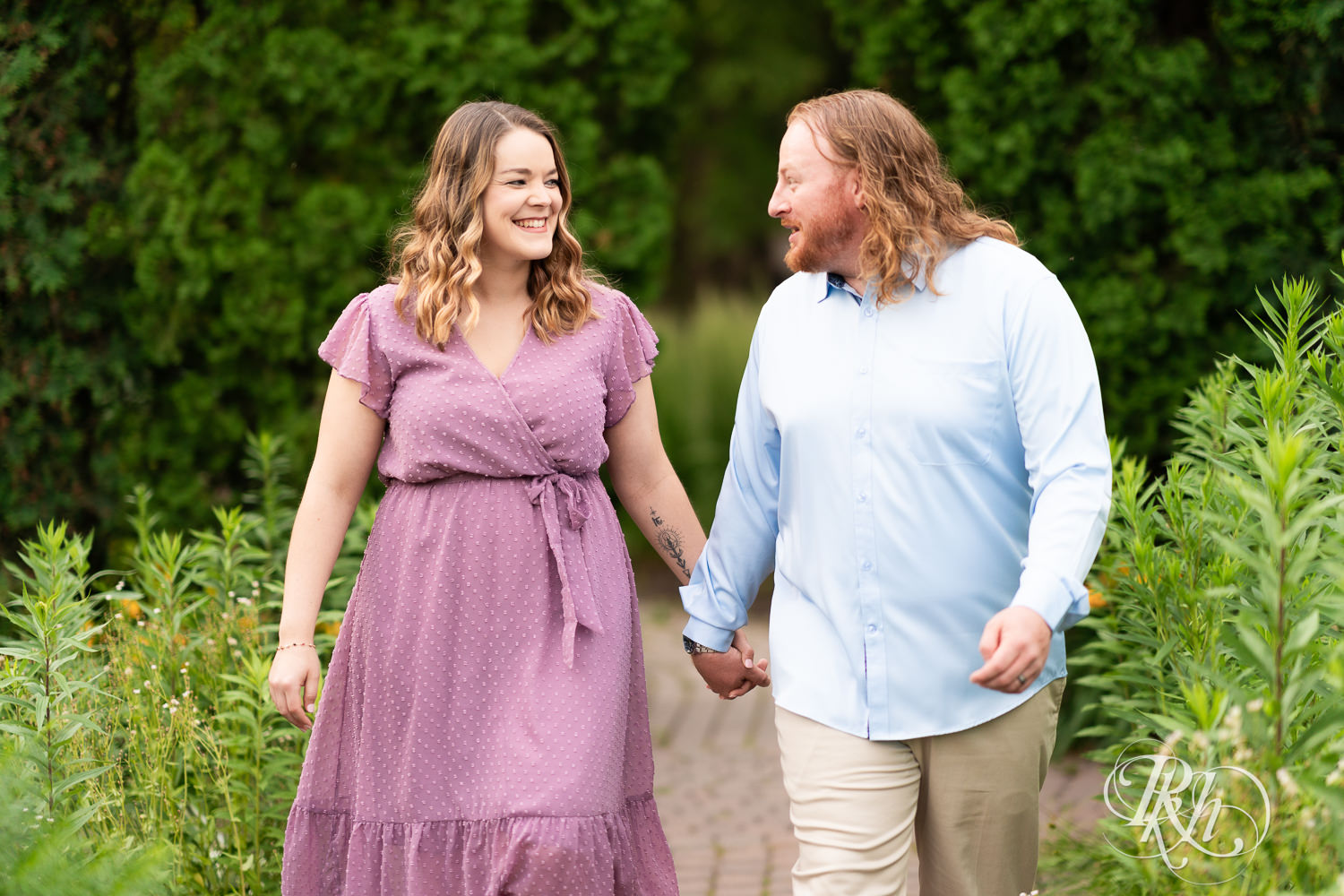 Man in blue shirt and woman in purple dress smile in a garden at Centennial Lakes Park in Edina, Minnesota.