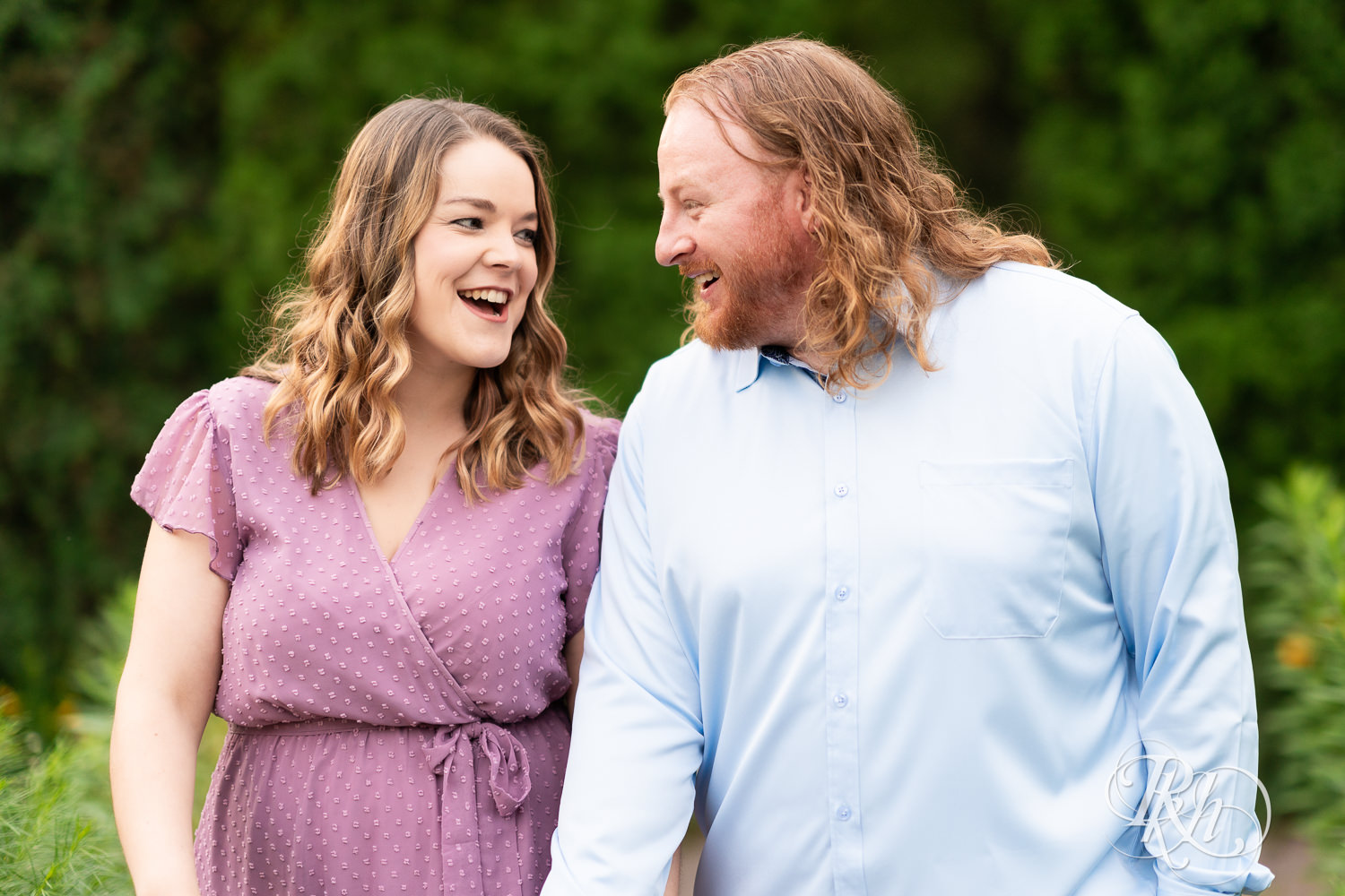 Man in blue shirt and woman in purple dress smile in a garden at Centennial Lakes Park in Edina, Minnesota.