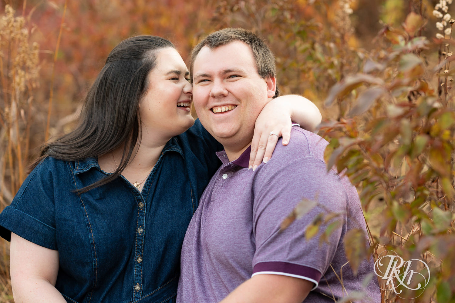 Plus size man and woman in blue dress smile at each other during engagement photos at Lebanon Hills Regional Park in Eagan, Minnesota.