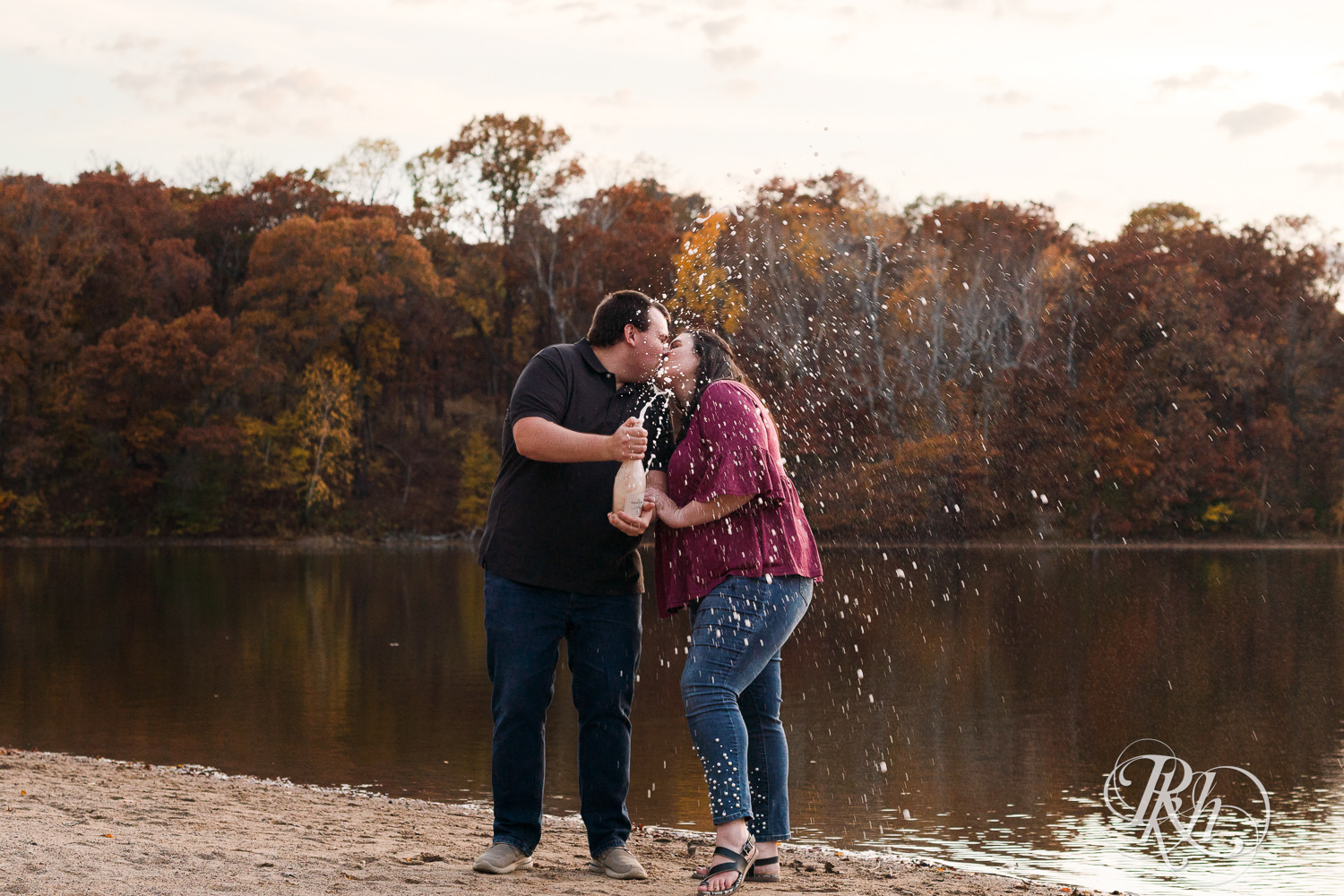 Plus size man and woman spray champagne on the beach at Lebanon Hills Regional Park in Eagan, Minnesota.