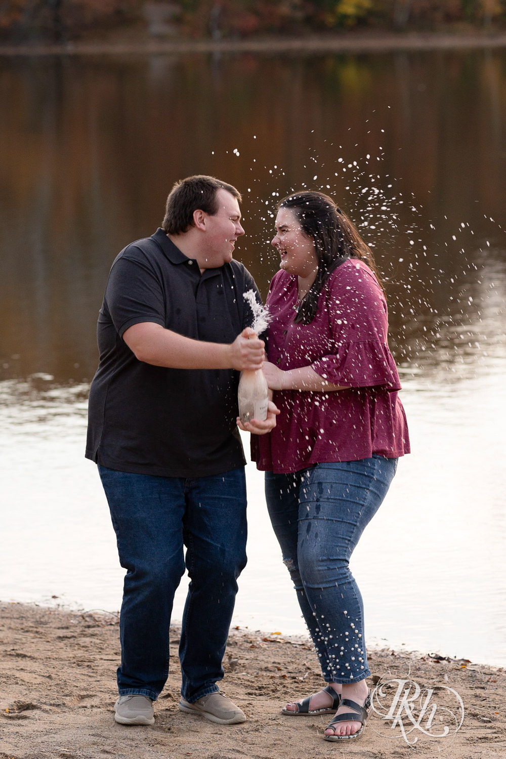 Plus size man and woman spray champagne on the beach at Lebanon Hills Regional Park in Eagan, Minnesota.