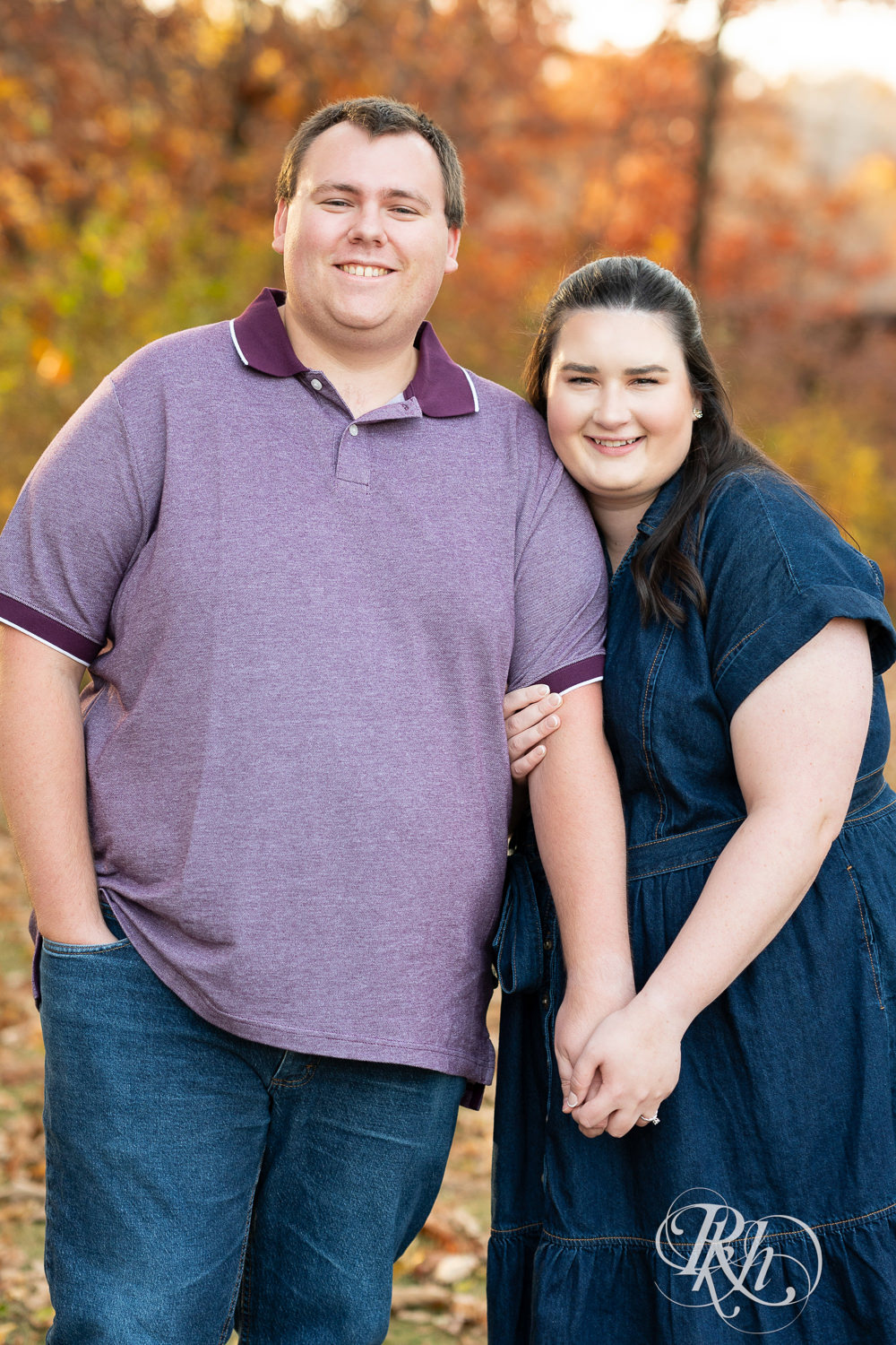 Plus size man and woman in blue dress smile at each other during engagement photos at Lebanon Hills Regional Park in Eagan, Minnesota.