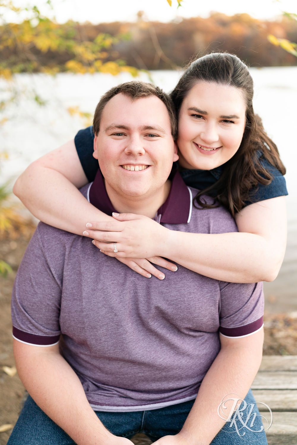 Plus size man and woman in blue dress smile at each other during engagement photos at Lebanon Hills Regional Park in Eagan, Minnesota.