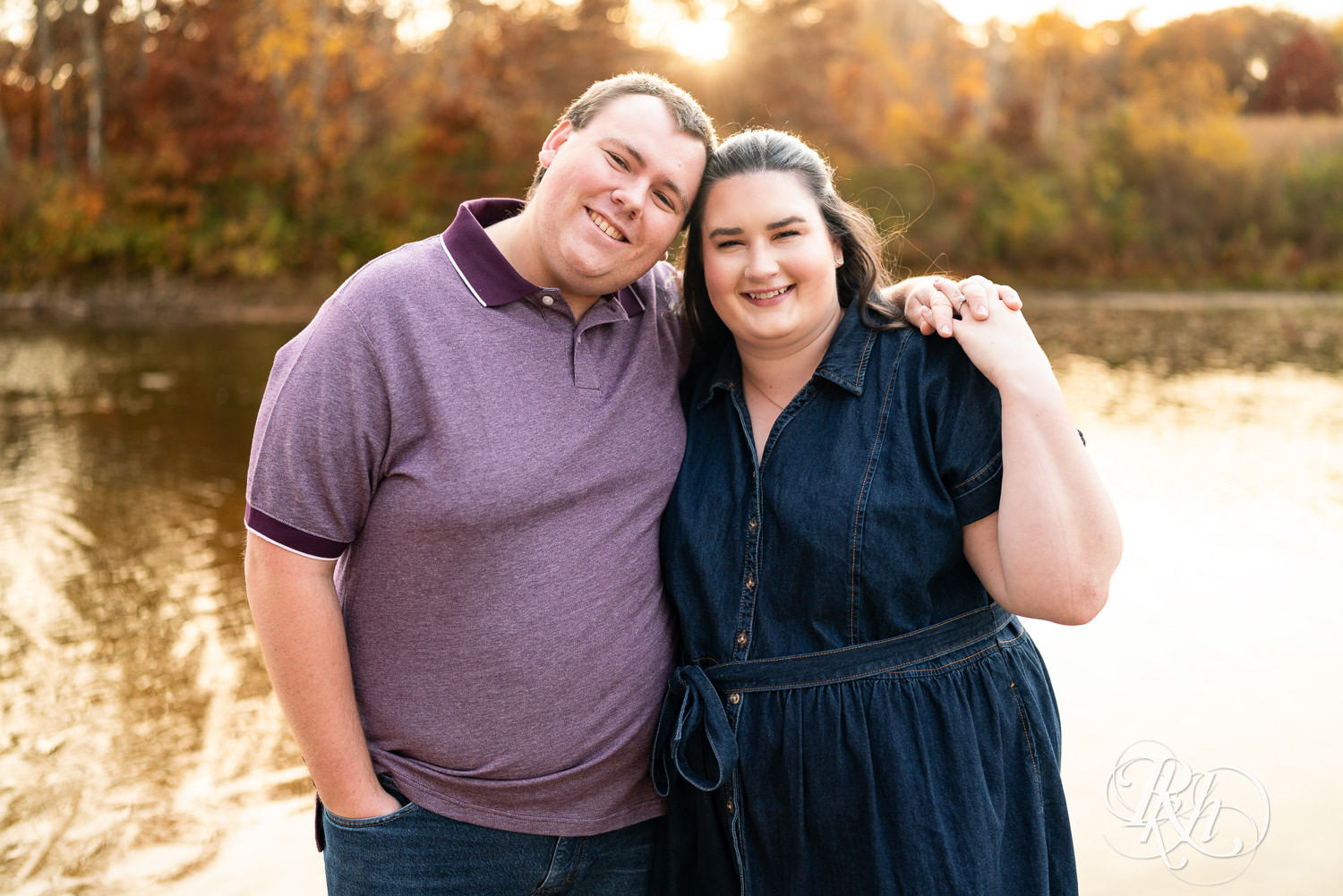 Plus size man and woman in blue dress smile at each other during engagement photos at Lebanon Hills Regional Park in Eagan, Minnesota.