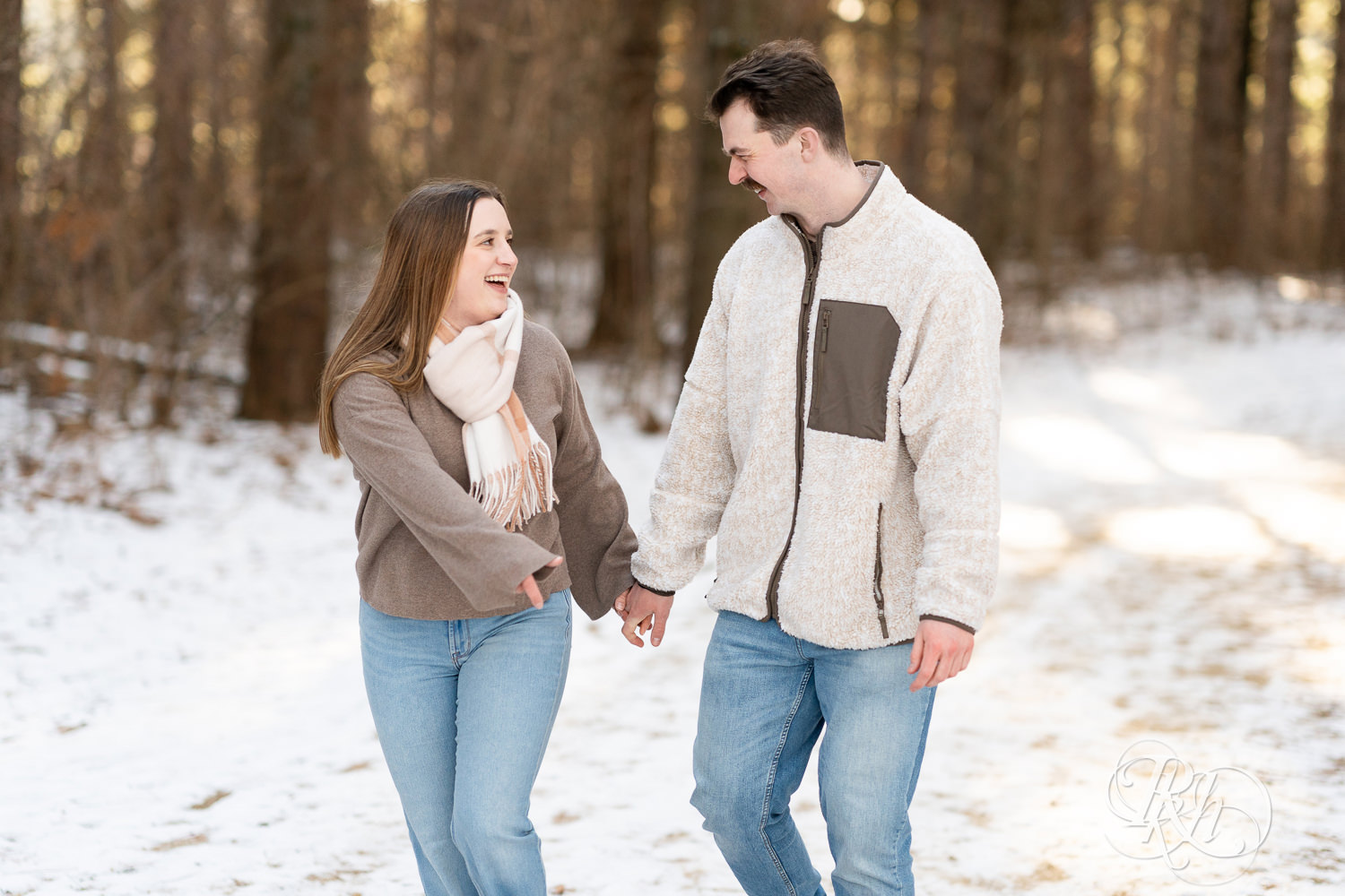 Man and woman walk in snow during winter engagement photos at Lebanon Hills Regional Park in Eagan, Minnesota.