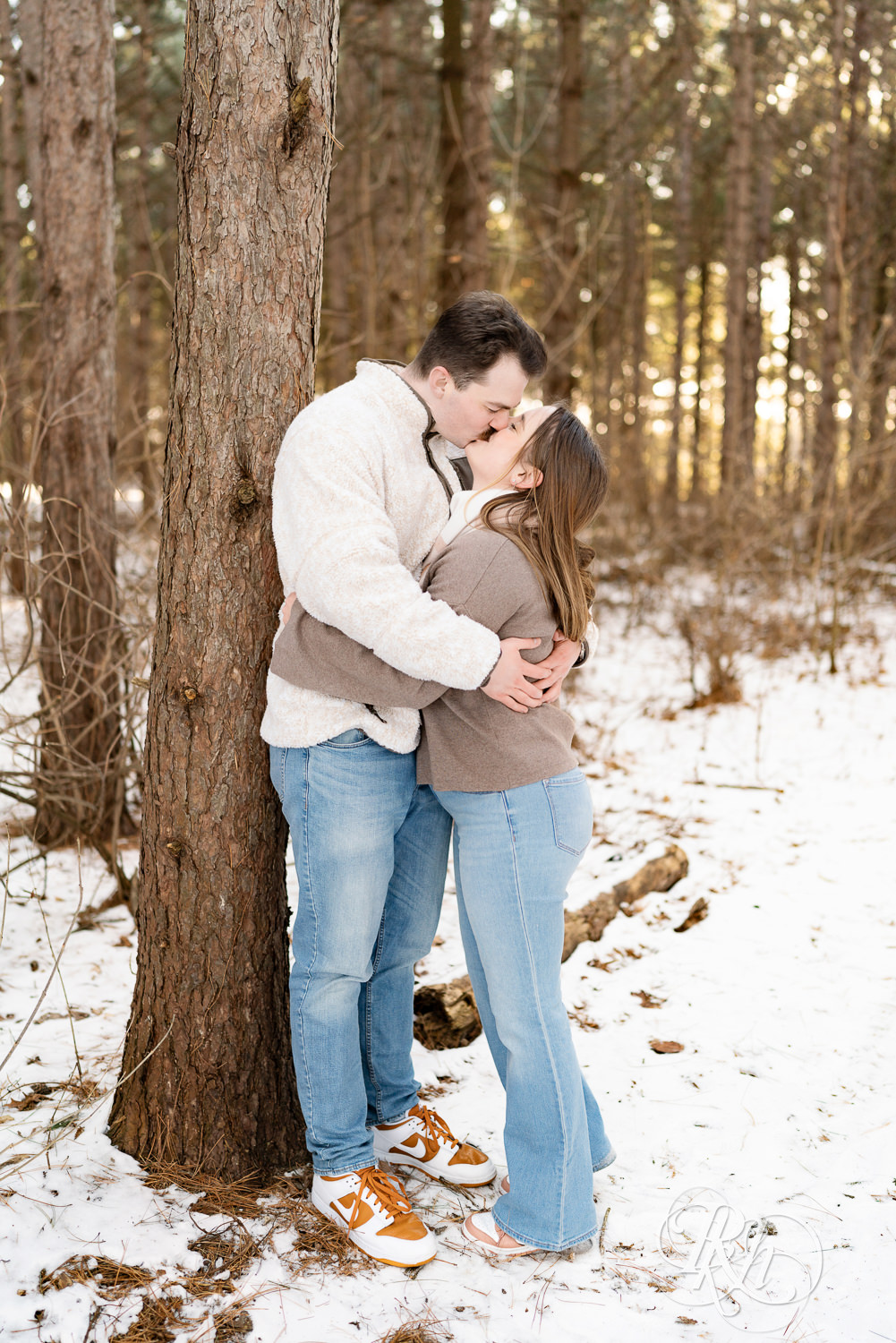 Man and woman kiss in forest during winter engagement photos at Lebanon Hills Regional Park in Eagan, Minnesota.