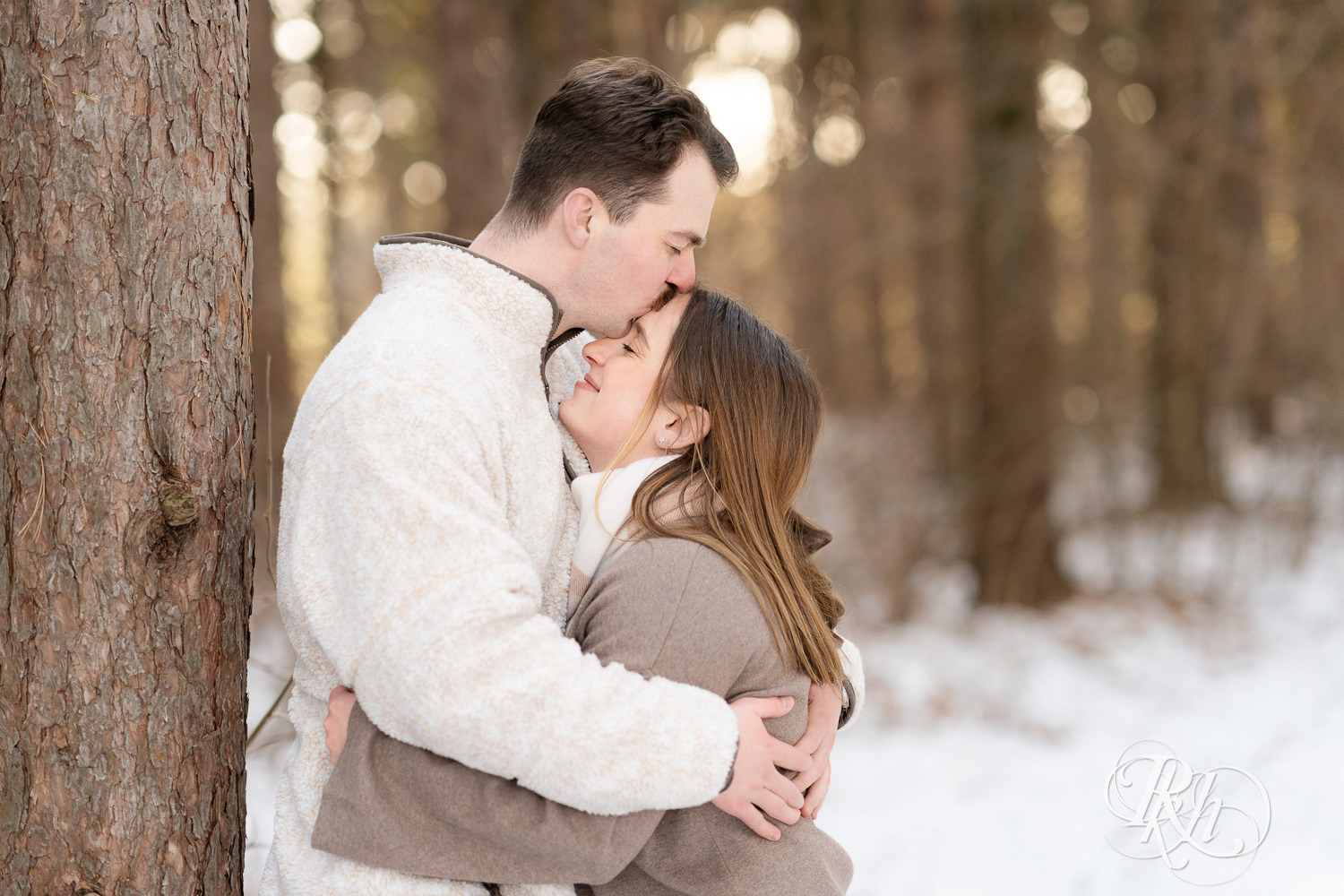 Man and woman kiss in forest during winter engagement photos at Lebanon Hills Regional Park in Eagan, Minnesota.