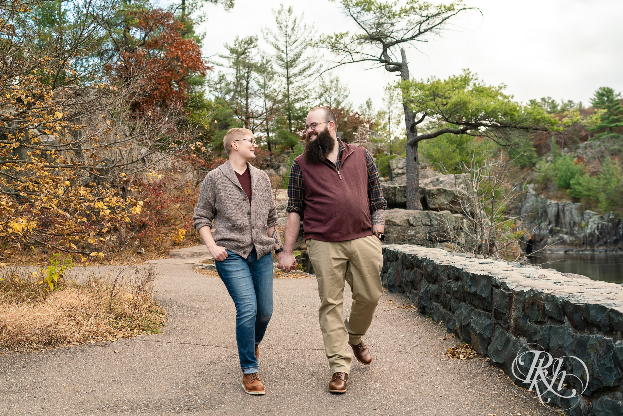 Man and non binary person walk along river during engagement photos in Taylor's Falls, Minnesota.