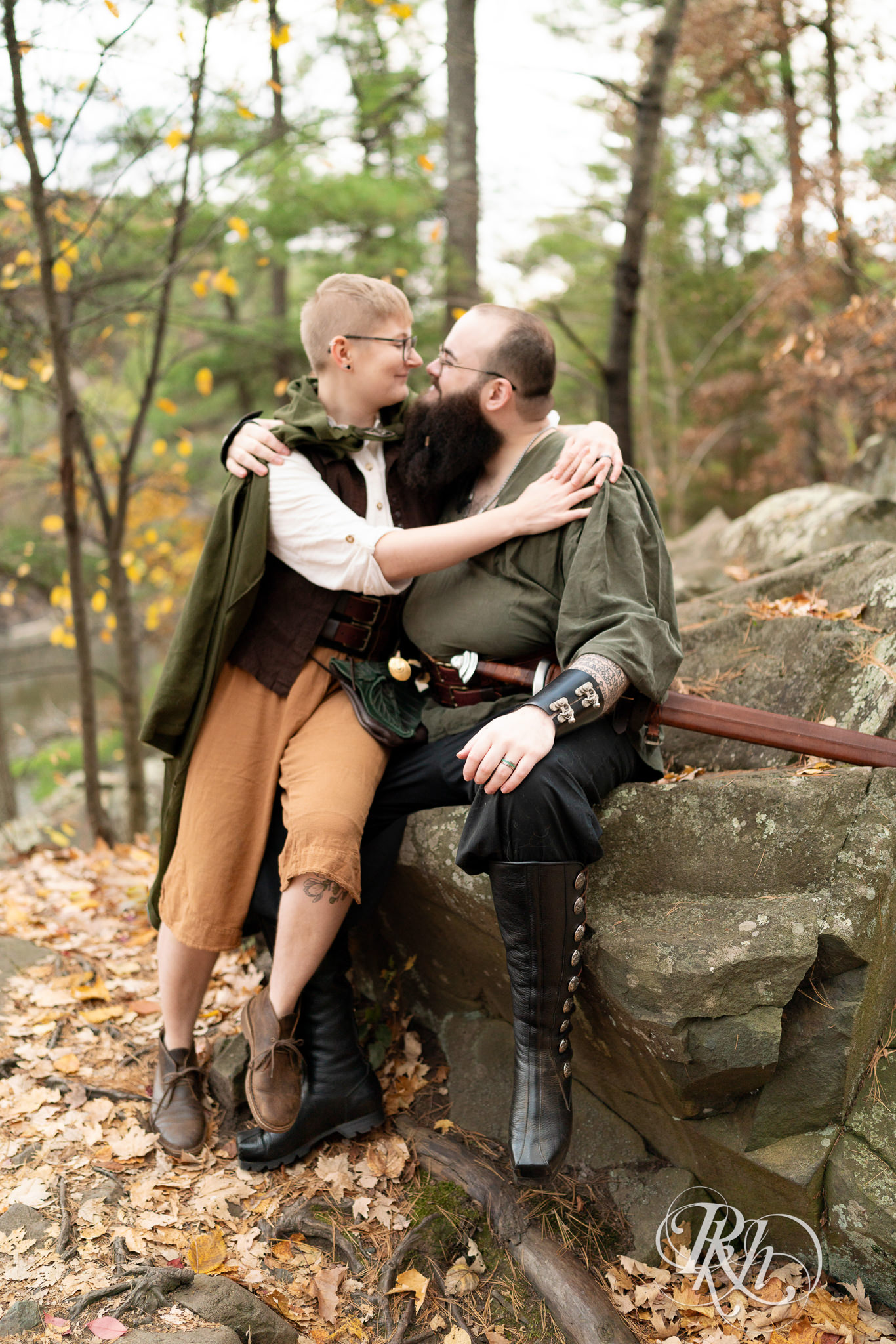 Man and non binary person in Renaissance outfits smile together on a cloudy day in Taylor's Falls, Minnesota.
