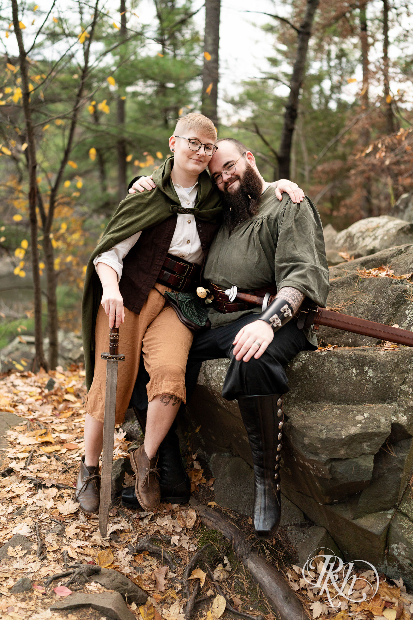 Man and non binary person in Renaissance outfits smile together on a cloudy day in Taylor's Falls, Minnesota.