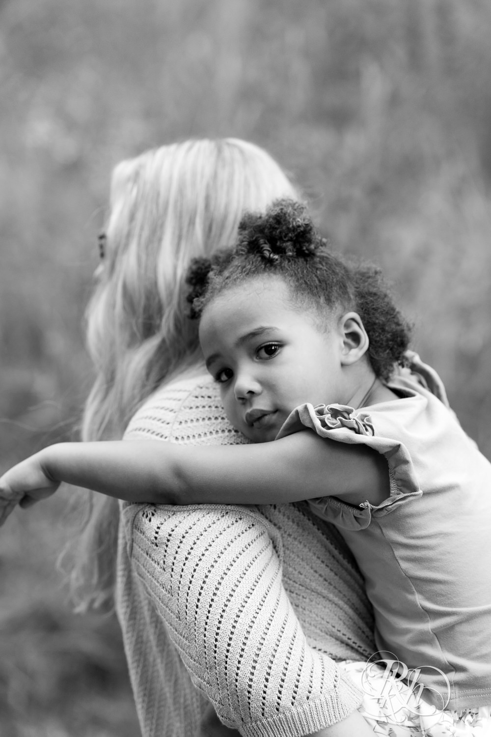 Little black girl clings to her mom as she carries her down a nature trail during sunset in Eagan, Minnesota.