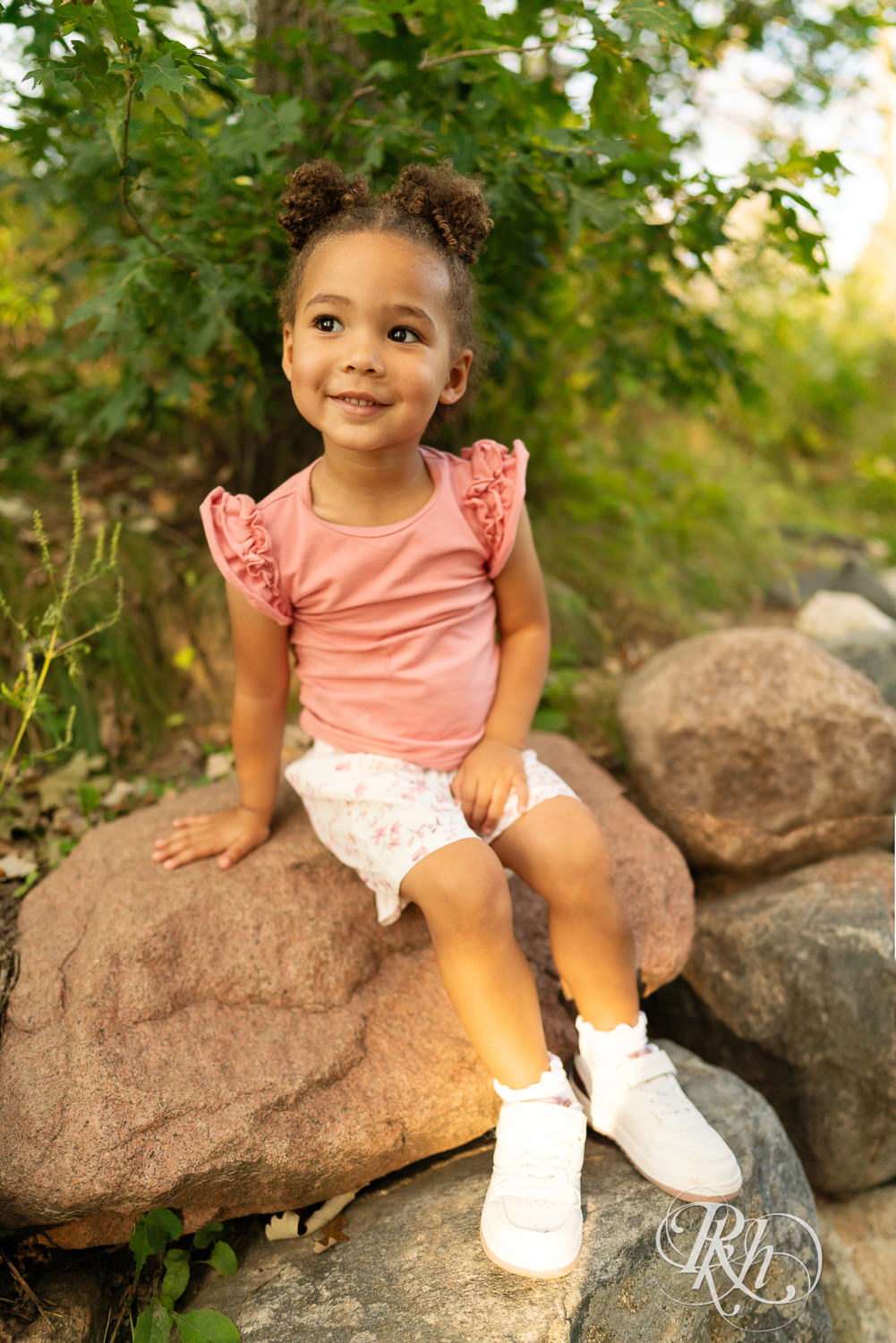 Little black girl smiles while sitting on a rock during sunset in Eagan, Minnesota.