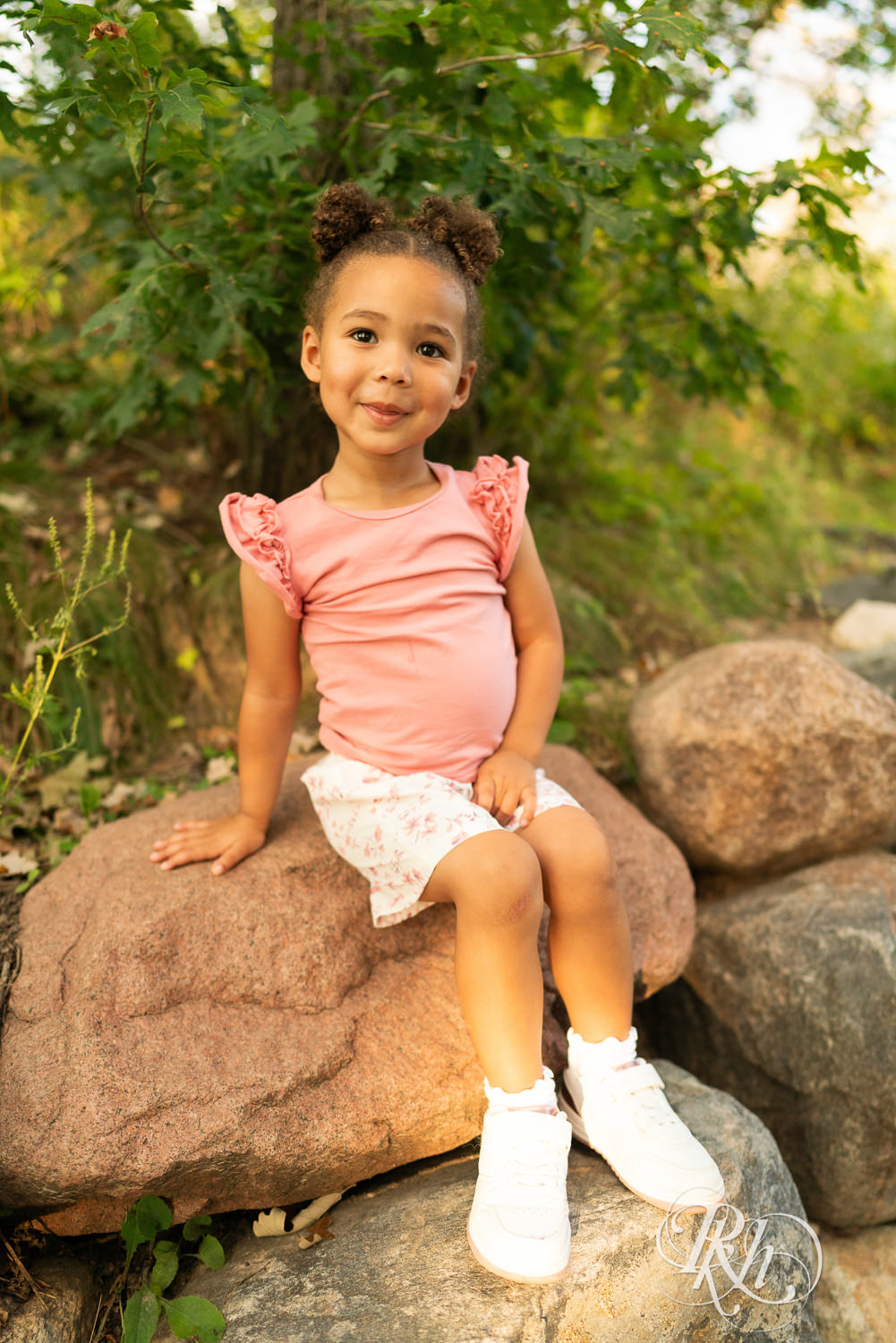 Little black girl smiles while sitting on a rock during sunset in Eagan, Minnesota.