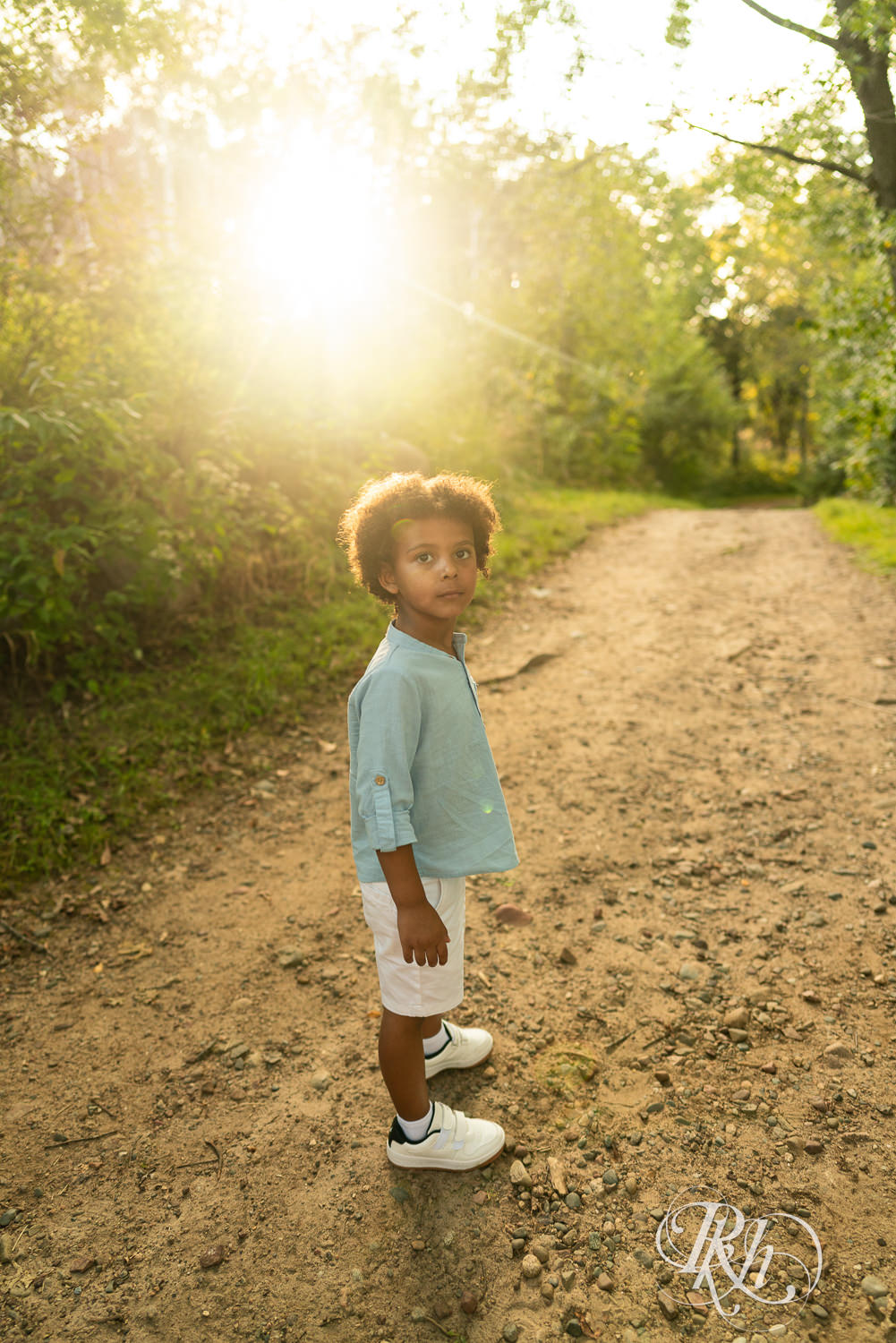 Little black boy walks down trail during sunset at Lebanon Hills Regional Park in Eagan, Minnesota.