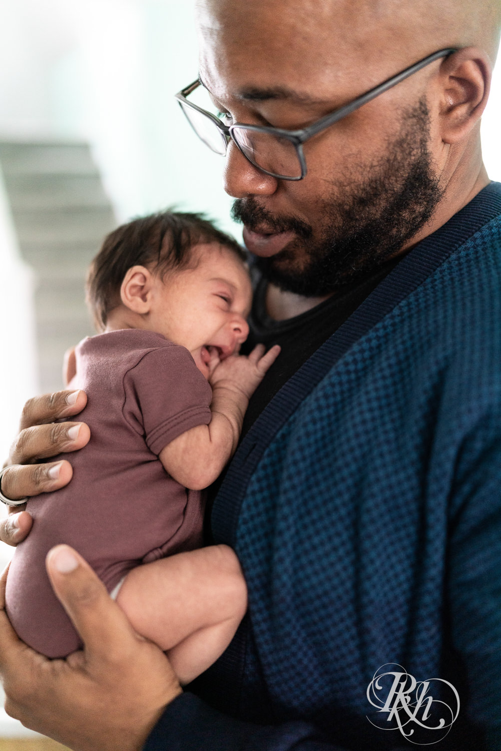 Black man snuggles with newborn baby at home in Saint Paul, Minnesota.