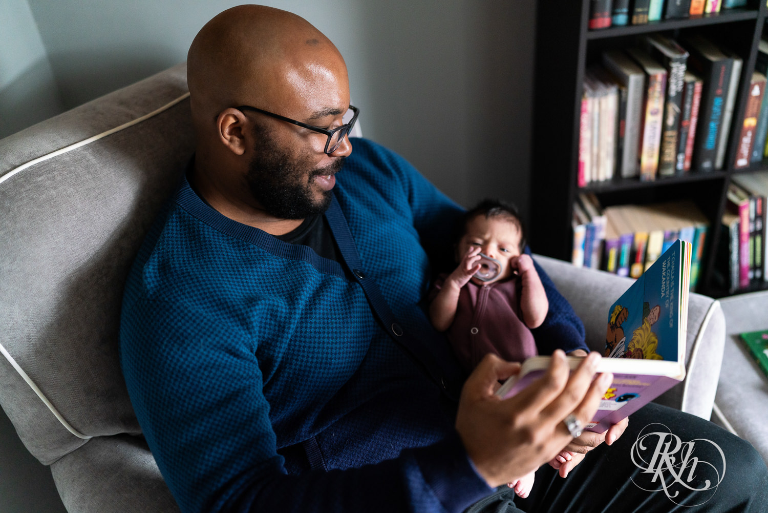 Black man reads to his newborn baby at home in Saint Paul, Minnesota.