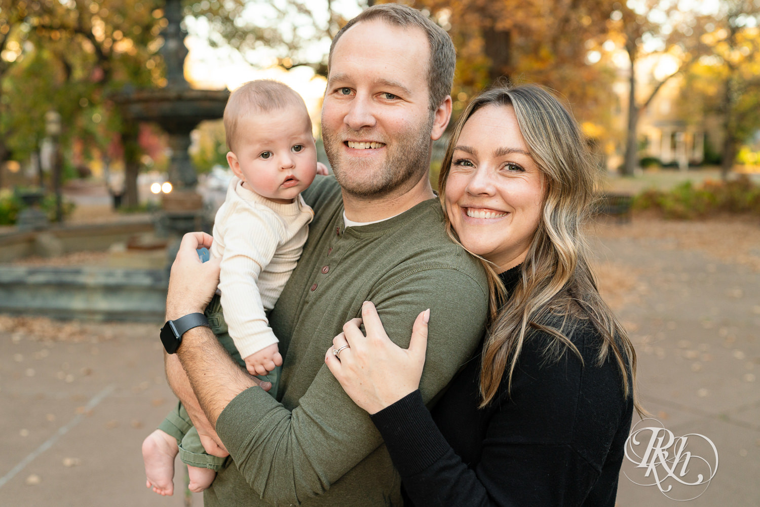 Mom and dad smile with baby during family photos at Irvine Park in Saint Paul, Minnesota.