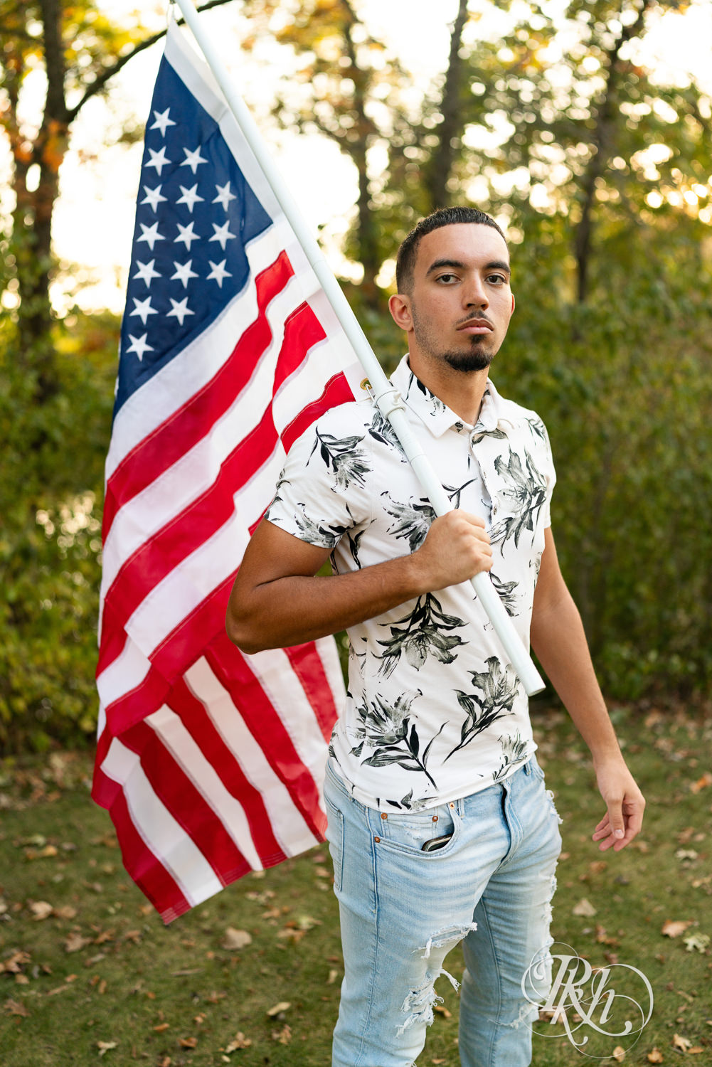 Black senior boy holds American flag during senior sunset photography in Eagan, Minnesota.