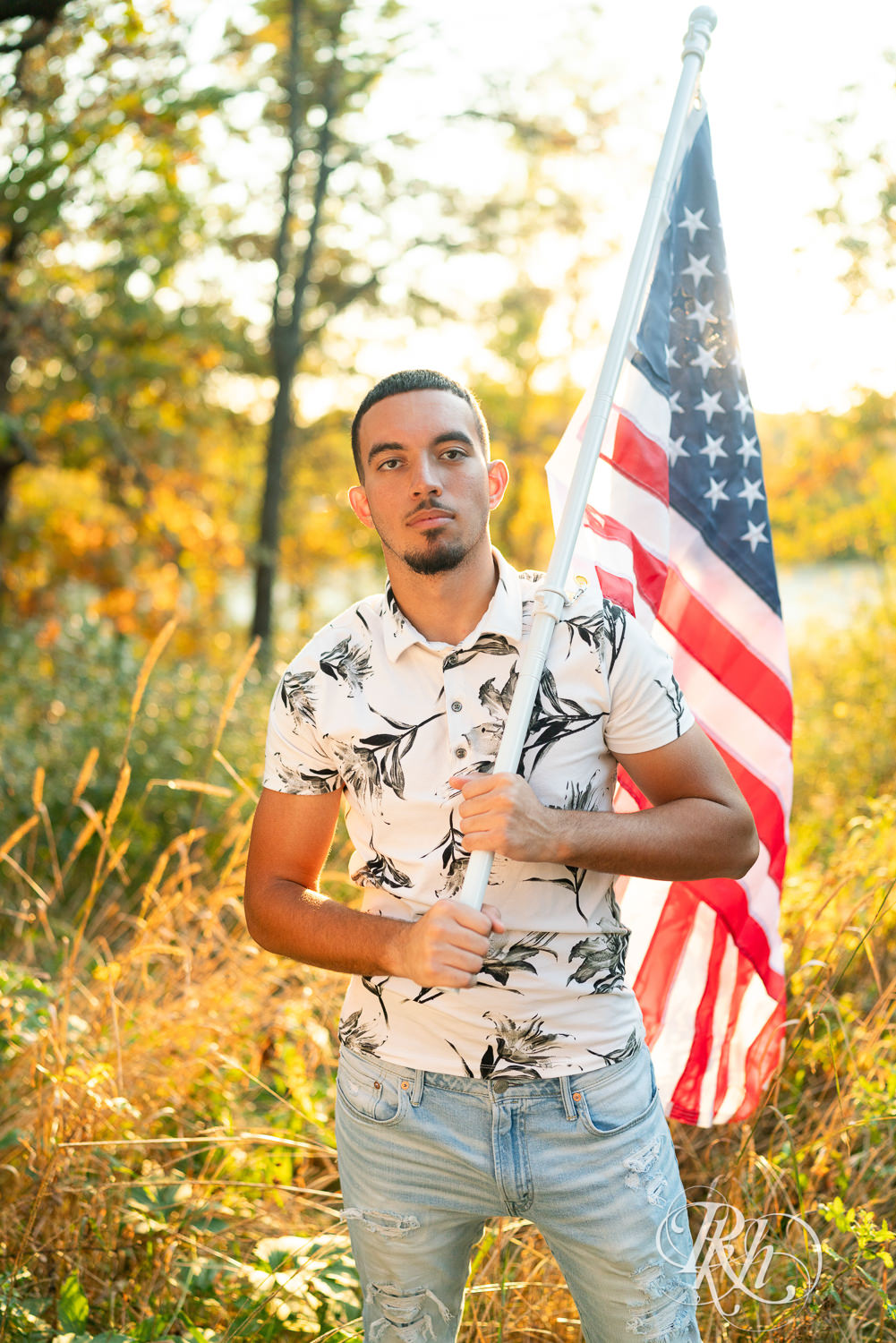 Black senior boy holds American flag during senior sunset photography in Eagan, Minnesota.