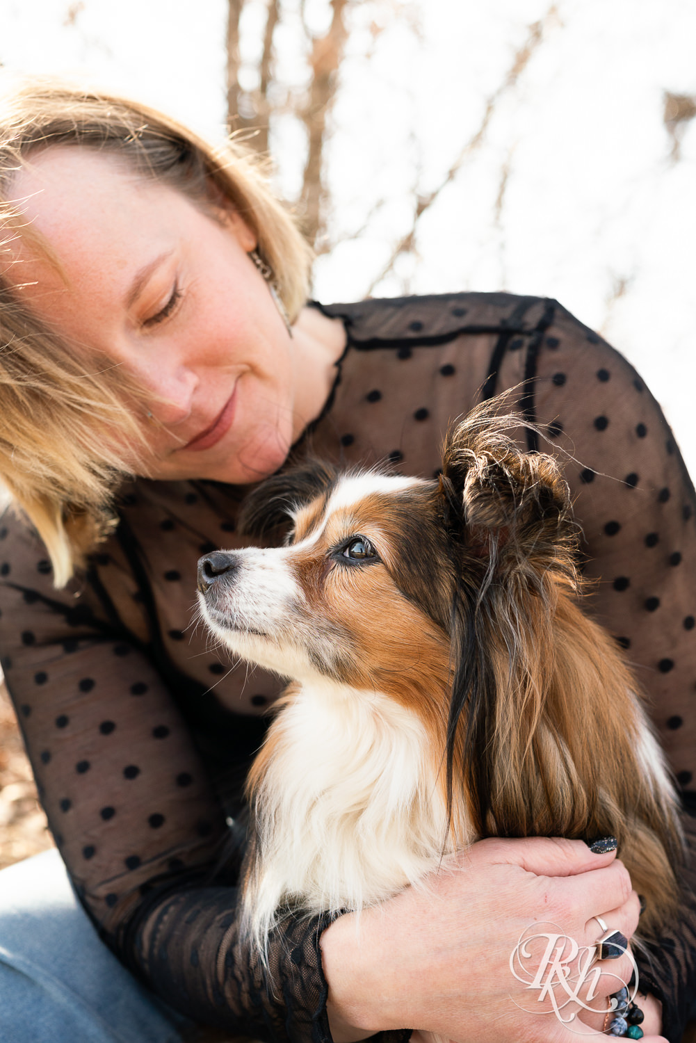 Blond woman holds her mini Aussie dog at Lebanon Hills Regional Park in Eagan, Minnesota during dog photography session.