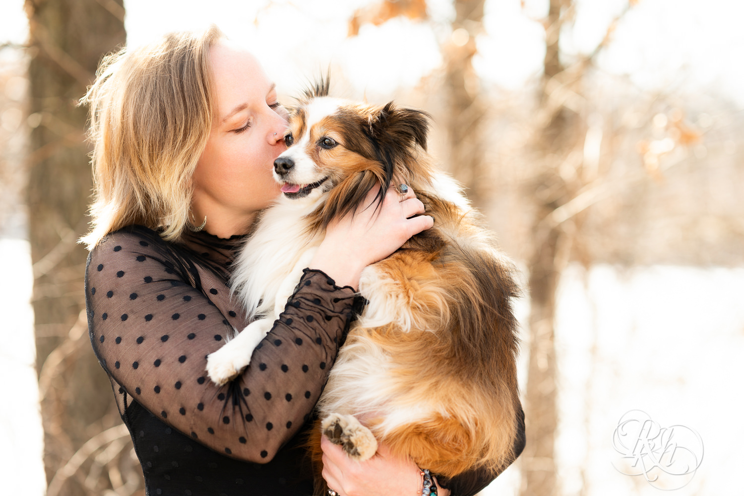 Blond woman holds her mini Aussie dog at Lebanon Hills Regional Park in Eagan, Minnesota during dog photography session.