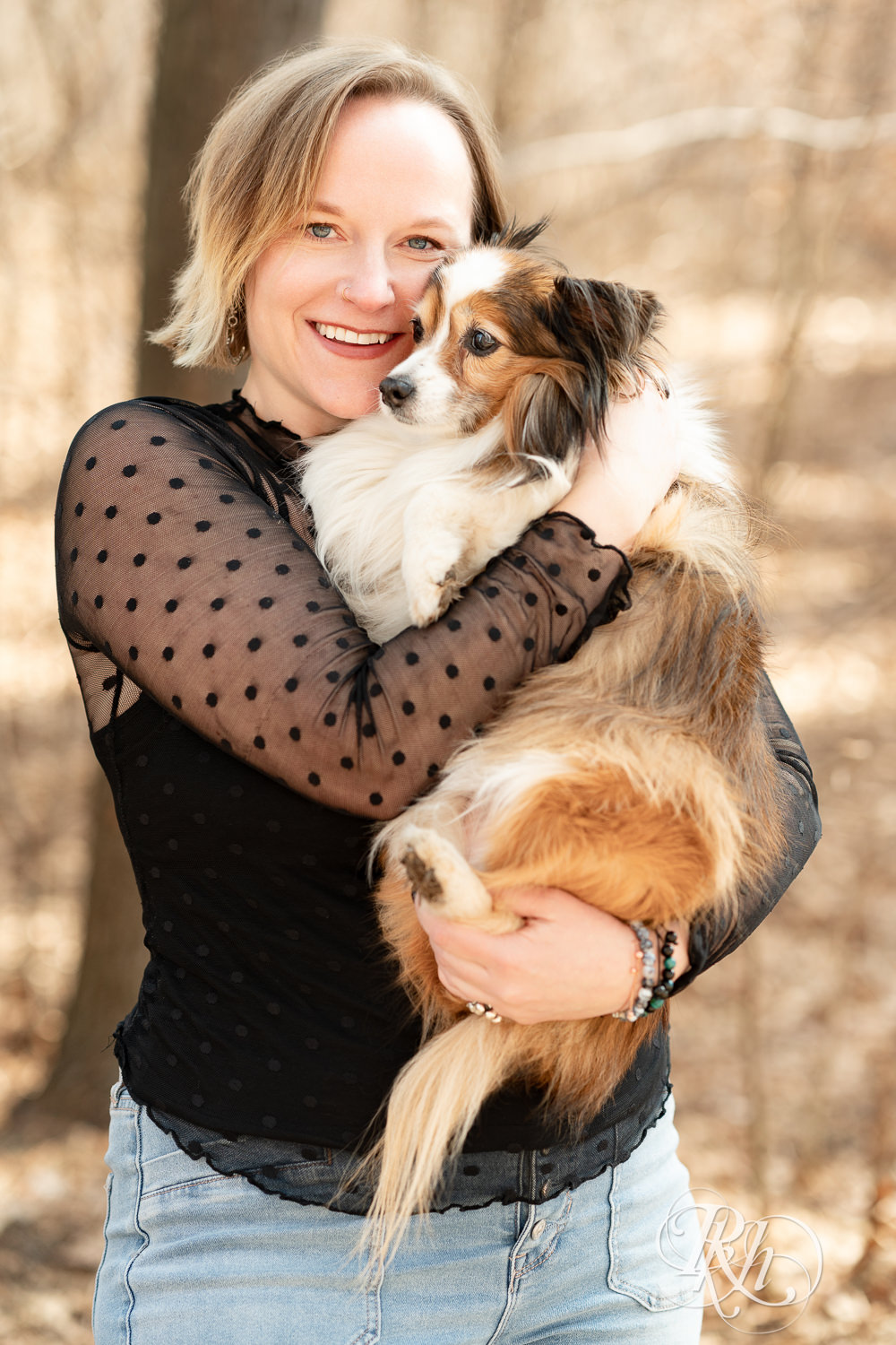 Blond woman snuggles her mini Aussie dog at Lebanon Hills Regional Park in Eagan, Minnesota during dog photography session.