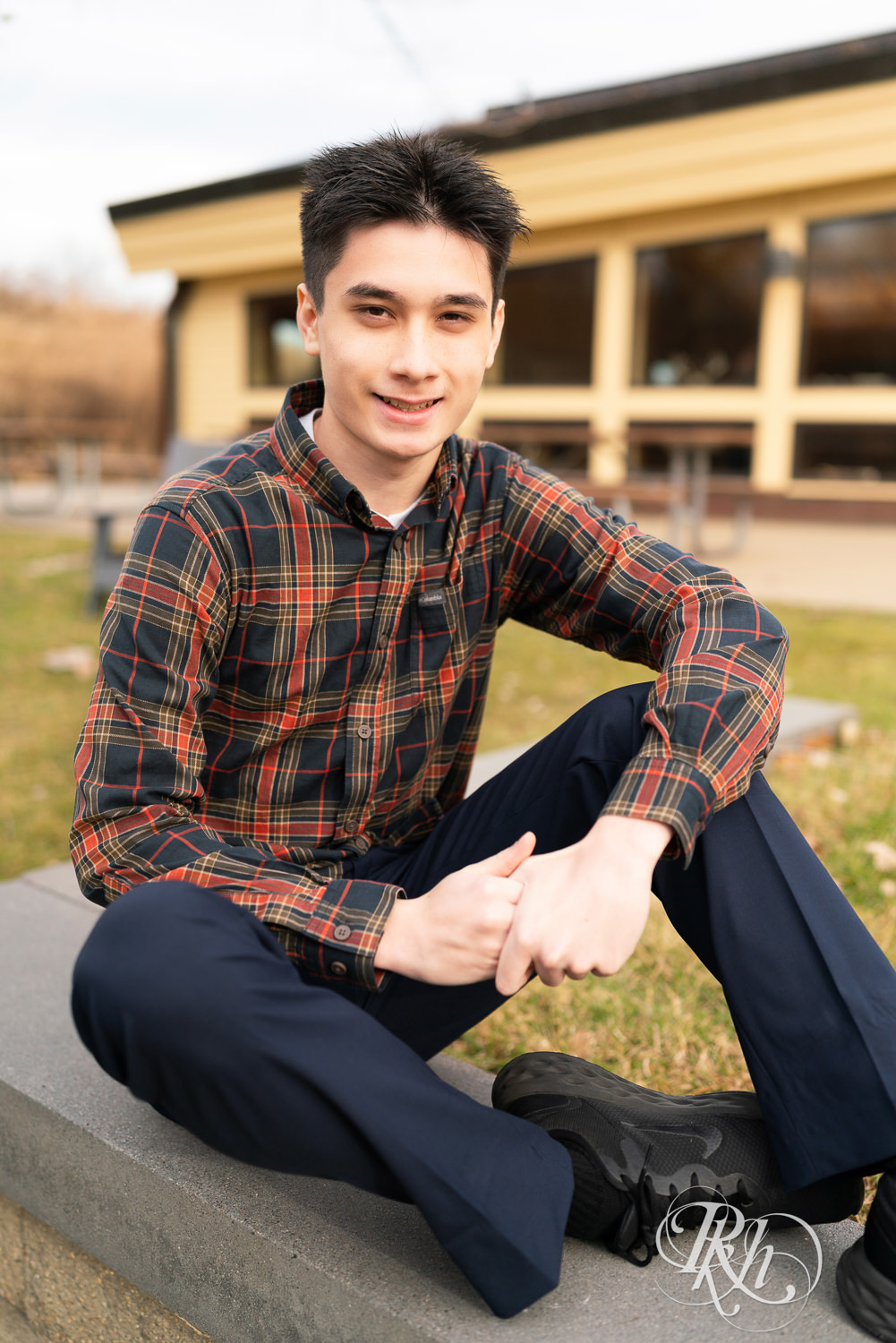 Asian senior boy in flannel smiles during senior photography at Lebanon Hills in Eagan, Minnesota.