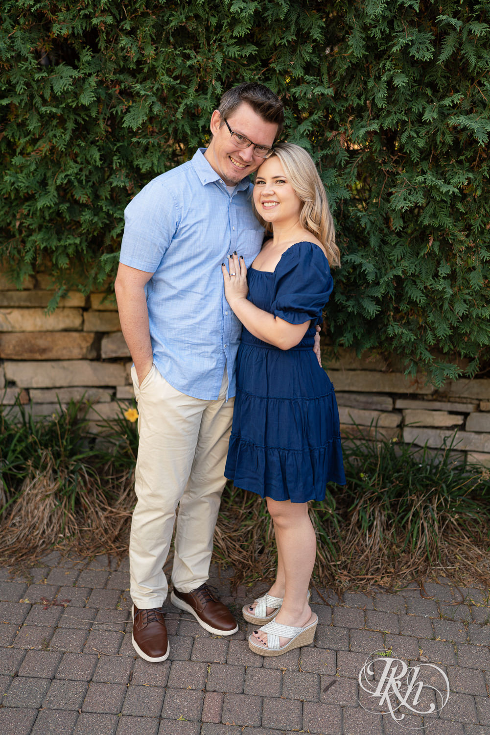 Man and woman in blue dress smile during morning engagement photography at Centennial Lakes Park in Edina, Minnesota.