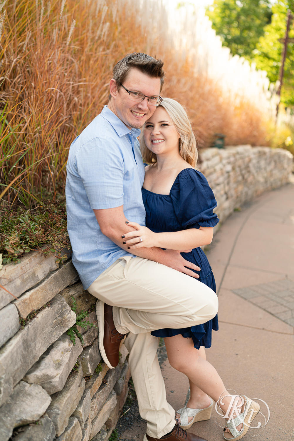 Man and woman in blue dress smile during morning engagement photography at Centennial Lakes Park in Edina, Minnesota.