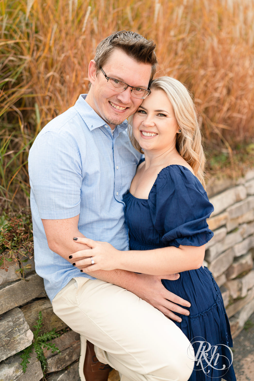 Man and woman in blue dress smile during morning engagement photography at Centennial Lakes Park in Edina, Minnesota.
